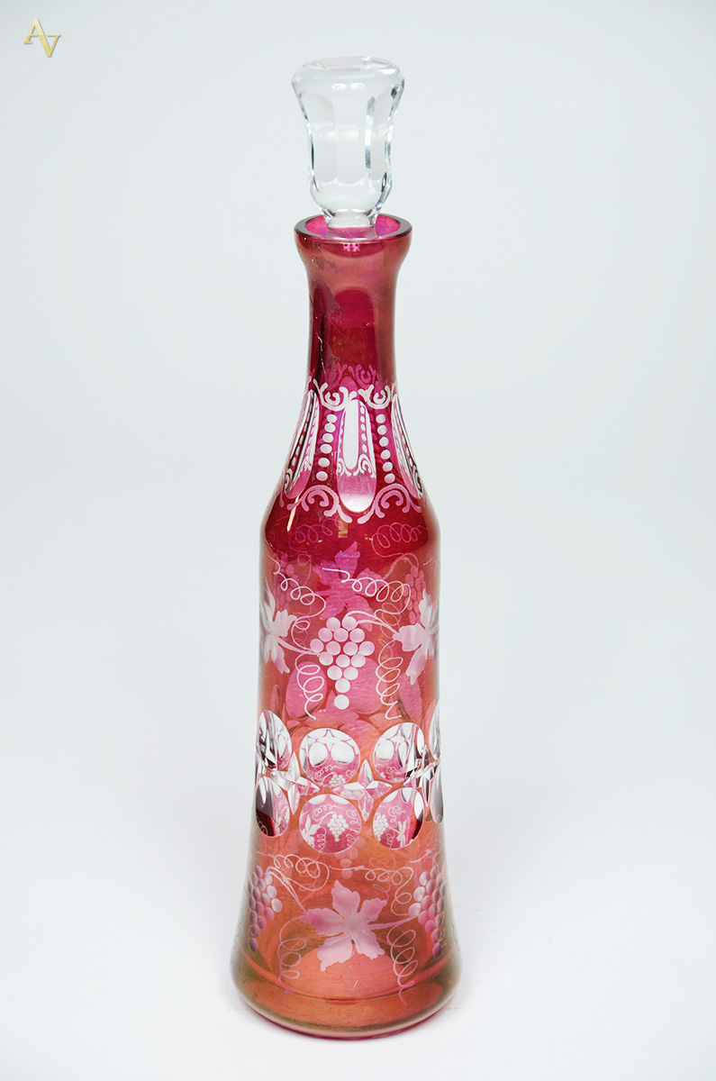 Garrafa de cristal na cor vermelha decorada com cachos de uvas...