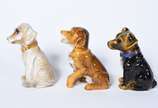 Três pequenas esculturas representando cachorro... - Três pequenas esculturas representando cachorros de porcelana policromada.