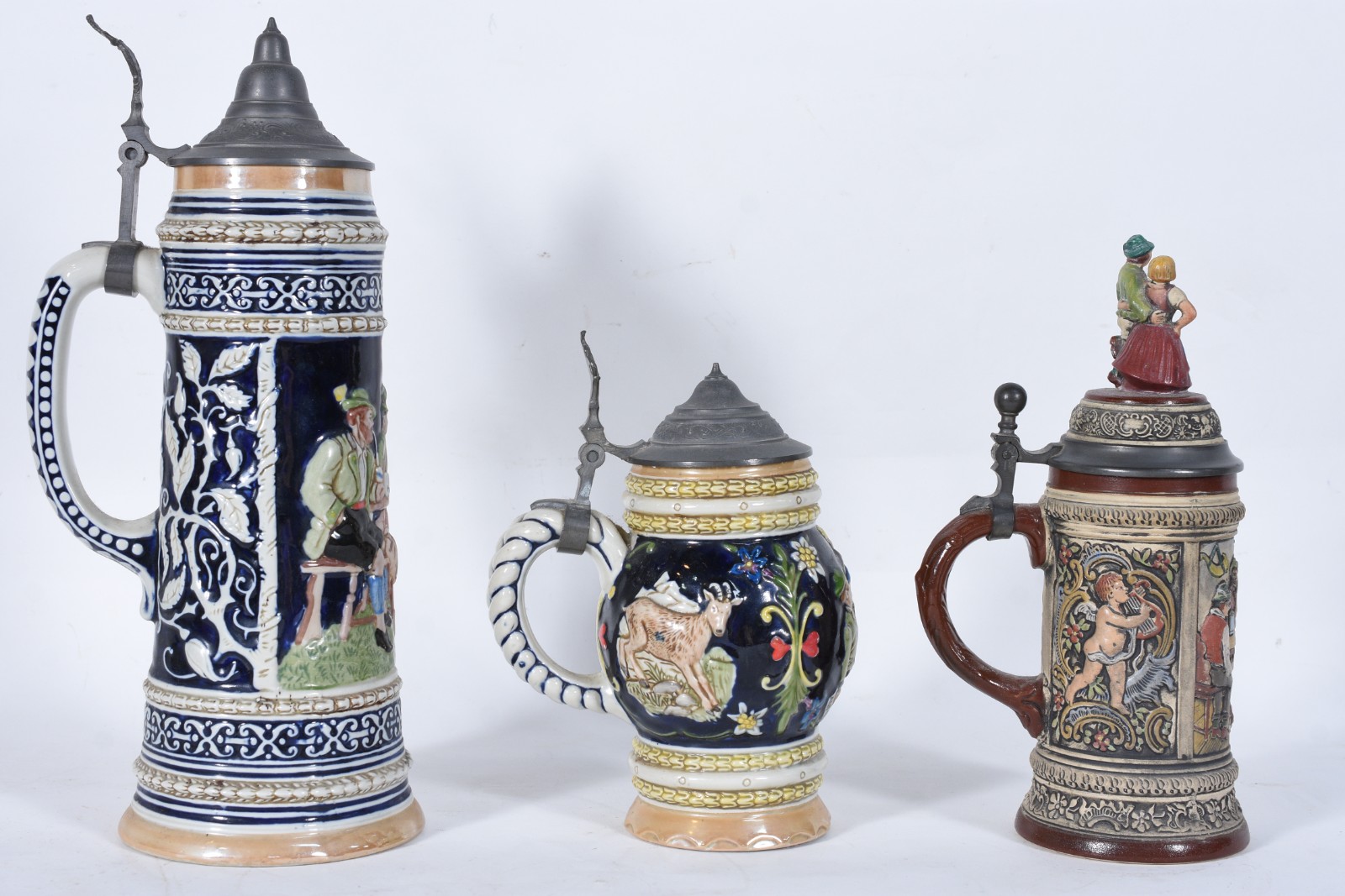Três canecas de cerâmica com figuras em relevo policromado, tampas de... - foto 1 de 10