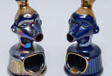 Par de cinzeiros de porcelana na cor azul cobal... - Par de cinzeiros de porcelana na cor azul cobalto repres. figuras estilizadas, realces dourados, alt. 16 cm.