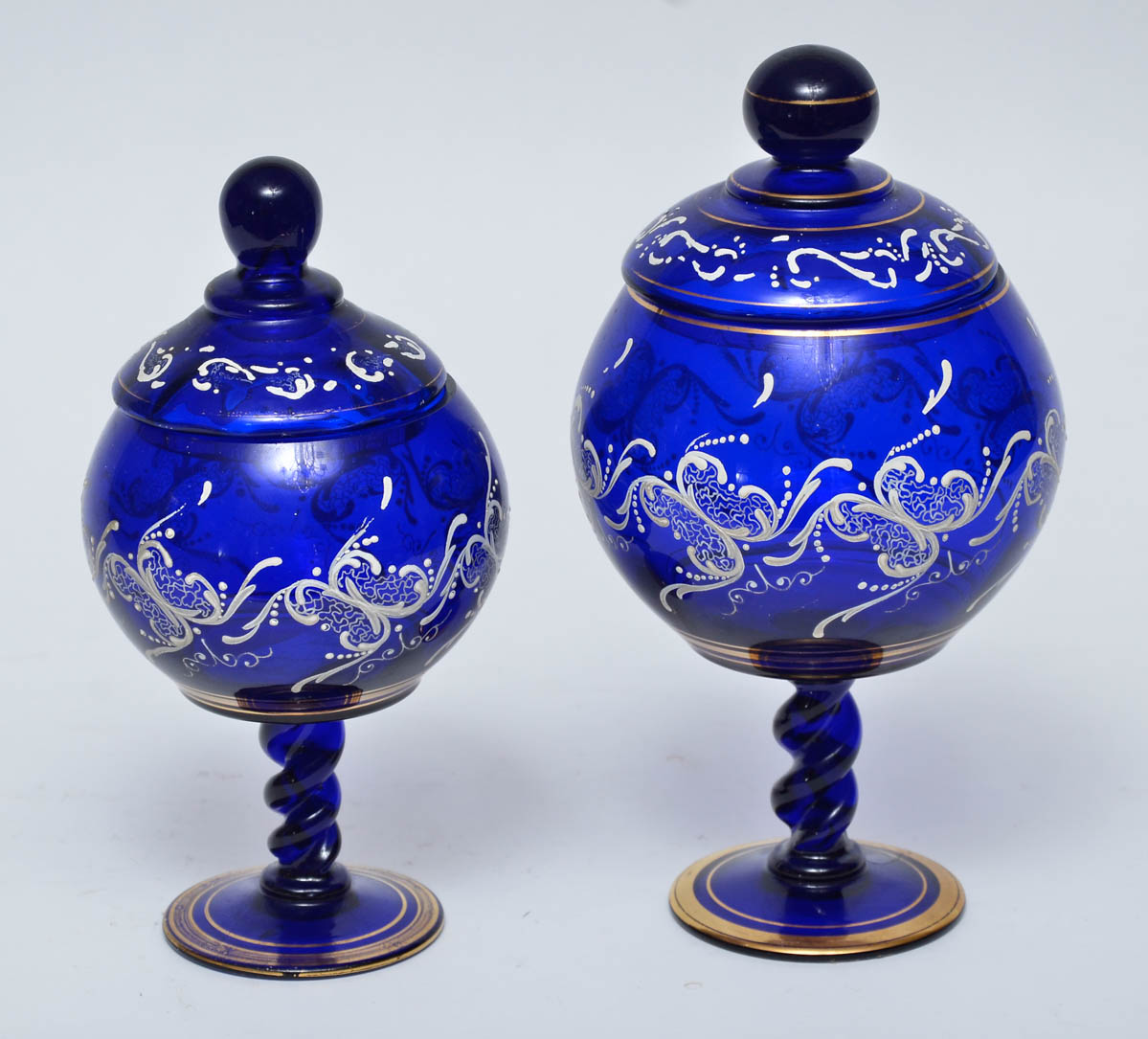 Duas bombonieres de vidro azul com frisos dourados. Alts. 25 e 29 cm.