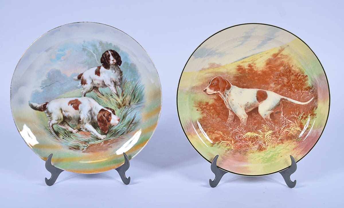 Dois pratos de porcelana decorados com figuras de cachorros em...