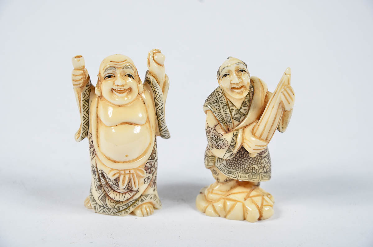 Dois netsukes de marfim, assinados, representando figuras. Alt. 5 cm.