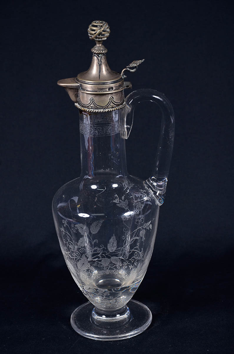 Garrafa com alça de cristal lavrado com borda de prata. Alt. 36 cm.
