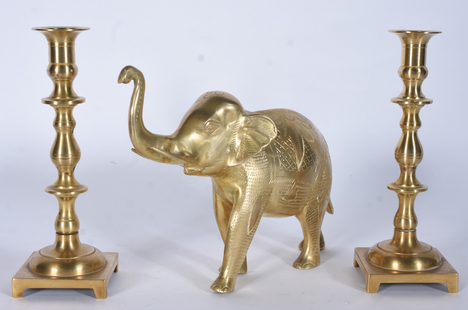 Tres peças de metal dourado, sendo par de castiçais e elefante. - foto 1 de 10