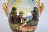 Vaso de faiança com paisagens em policromia, pe... - Vaso de faiança com paisagens em policromia, pegas laterais recortadas em tons de amarelo e azul.
