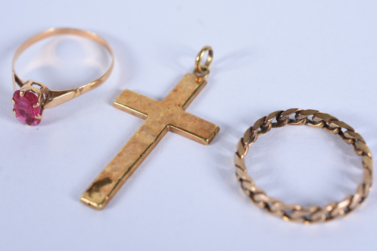 Três peças de ouro baixo, sendo: crucifixo, anel com pedra vermelha... - foto 1 de 9