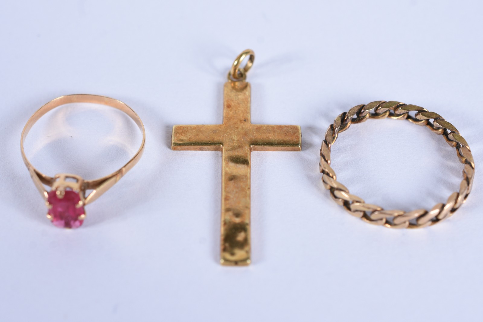 Três peças de ouro baixo, sendo: crucifixo, anel com pedra vermelha... - foto 2 de 9