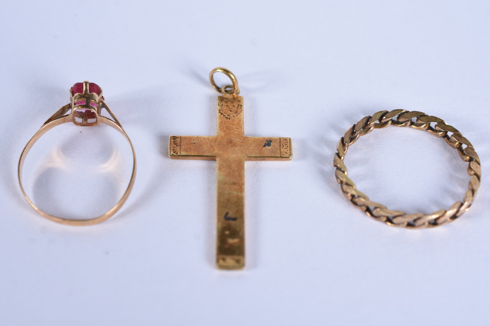 Três peças de ouro baixo, sendo: crucifixo, anel com pedra vermelha... - foto 3 de 9