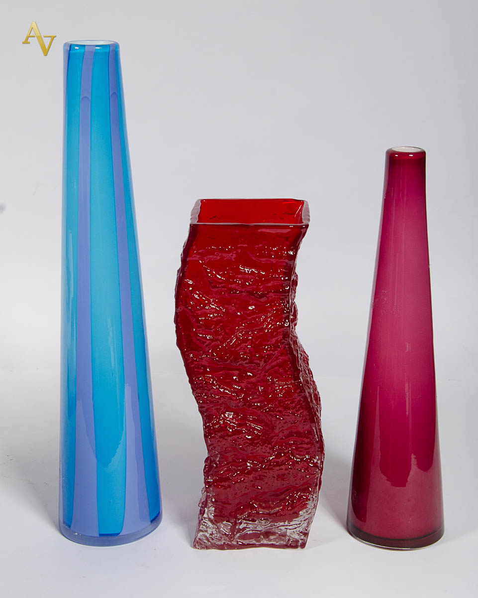Tres vasos de vidro, sendo 1 na cor vermelha; 1 turquesa e outro...