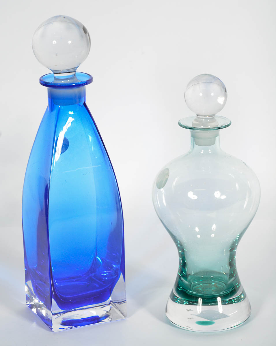 Duas garrafas de cristal, sendo 1 verde e outra azul. Alts. 27 e 33...