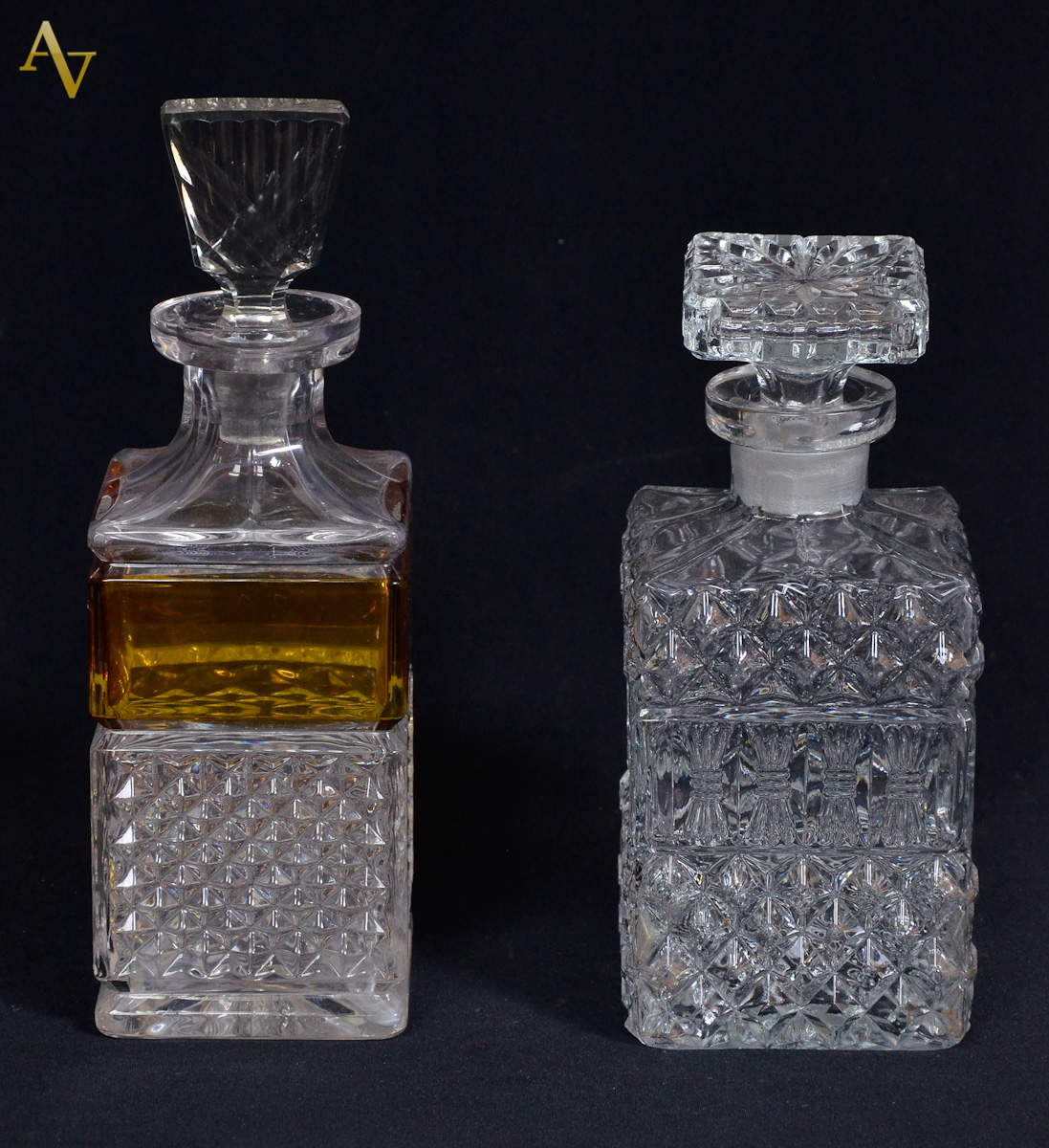 Duas garrafas em demi cristal sendo uma com faixa na cor âmbar...