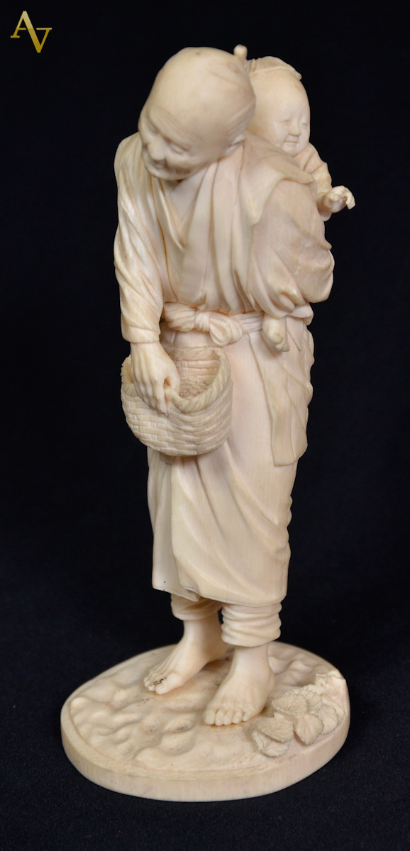 Estatueta de marfim com crianca nas costas. Selo vermelho - Alt.19 cm.