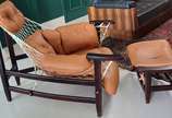 Poltrona "Jangada" com estrutura em madeira cum... - Poltrona "Jangada" com estrutura em madeira cumaru, estofado em couro natural na cor caramelo sustentado por rede de cordas,  acompanhando banqu...