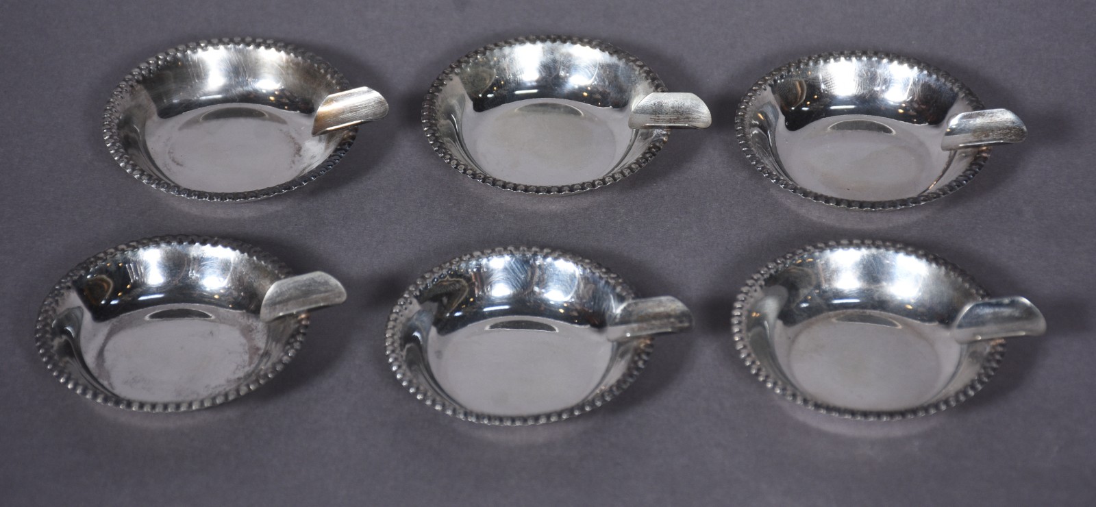 Seis cinzeiros individuais de metal prateado com bordas peroladas. - foto 1 de 5