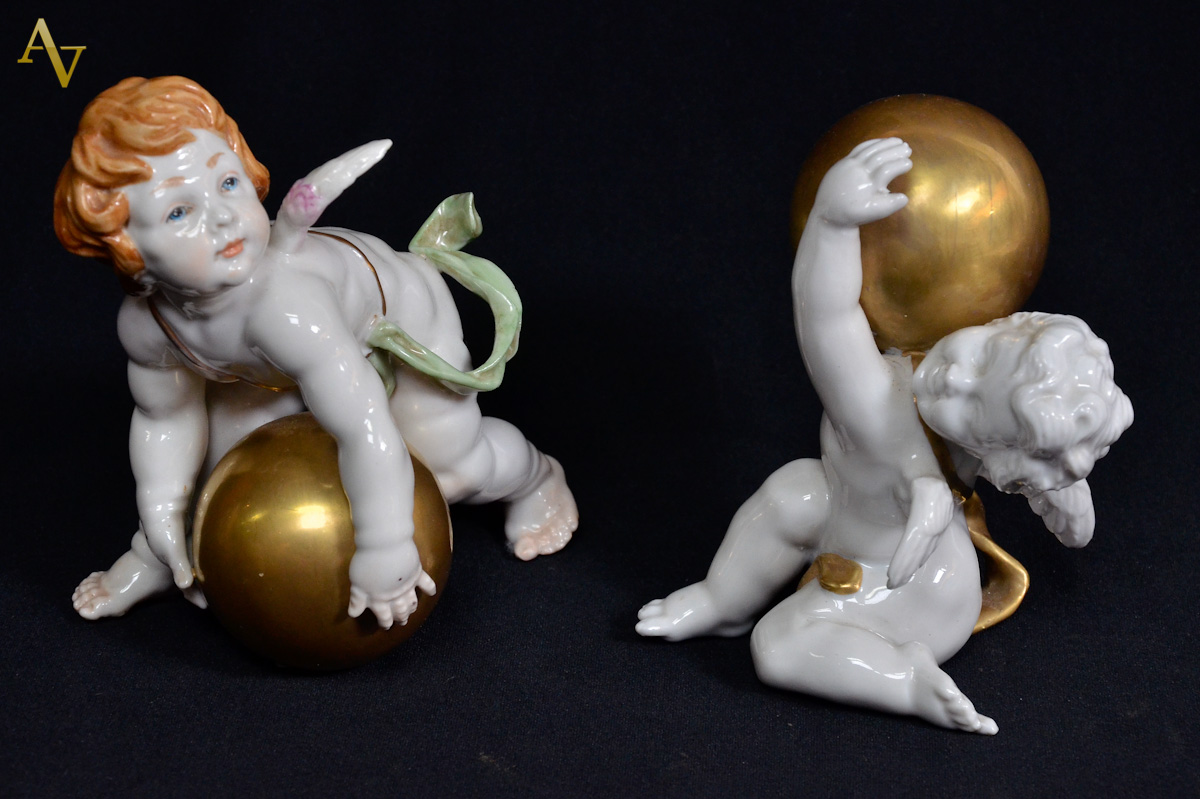 Duas estatuetas de porcelana européia representando anjos com esferas...