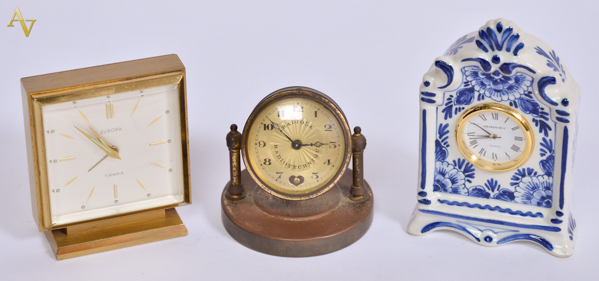 Tres pequenos relogios, sendo um de porcelana de Delft, um de bronze...