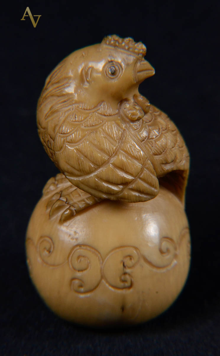 Netsuke de marfim repres galinha sobre bola.