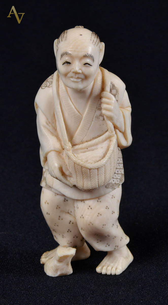 Okinomo em marfim ass ,representando homem com cesto; alt 8cm