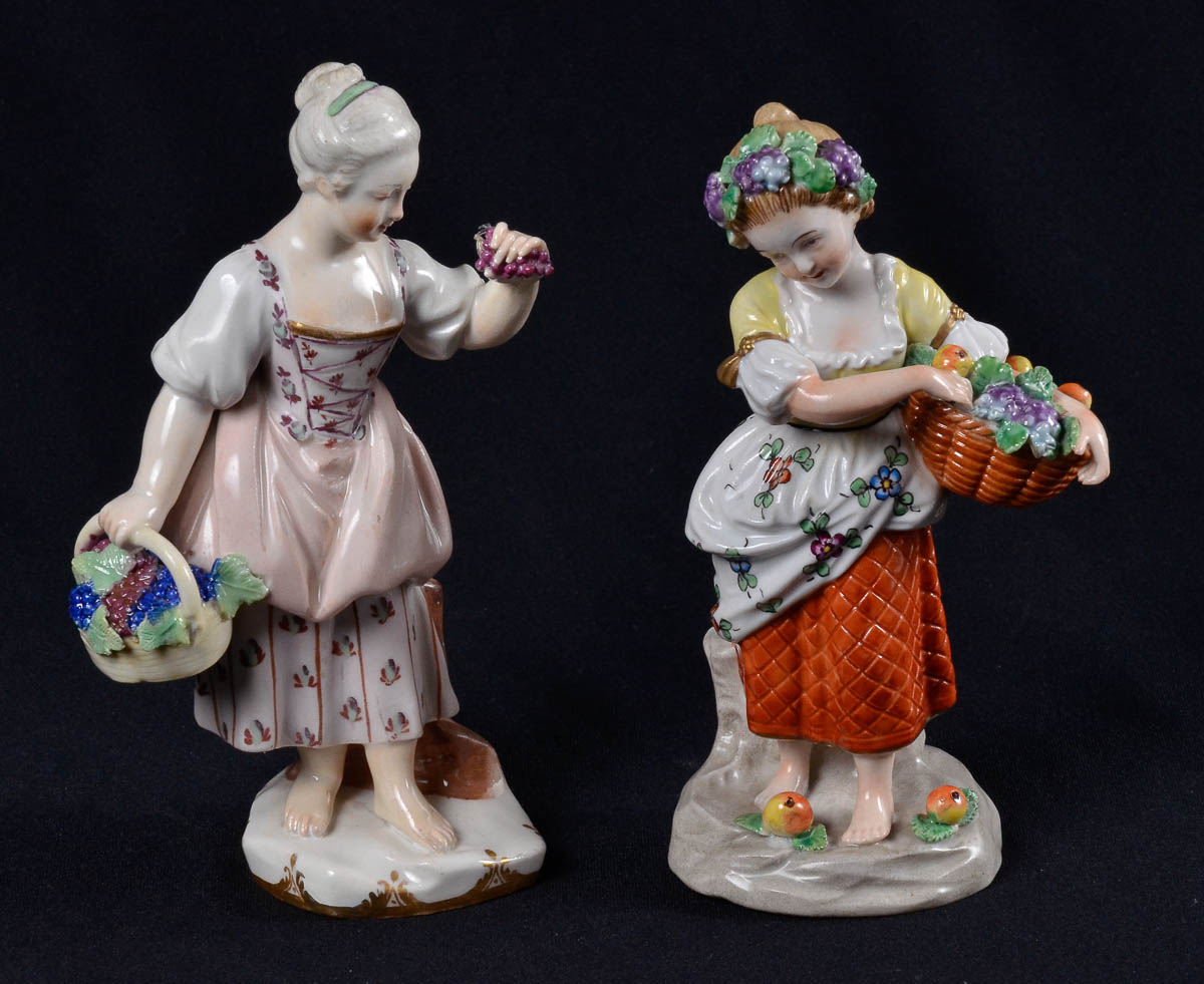 Duas estatuetas de porcelana européia repres. menina c/ cesto de uva...