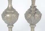 Par de ânforas de metal com anjos, flores e fol... - Par de ânforas de metal com anjos, flores e folhagens em relevo. Uma delas com aplique de figura alada estilizada. Desgastes no metal.