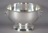 Grande bowl de metal prateado, bordas com cordo... - Grande bowl de metal prateado, bordas com cordoados, pegas laterais na forma de cabeças de leão em relevo com argolas. Desgastes.