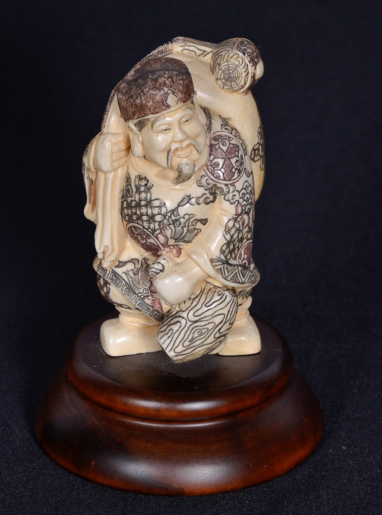 Estatueta de marfim repres. figura com saco, base de madeira...