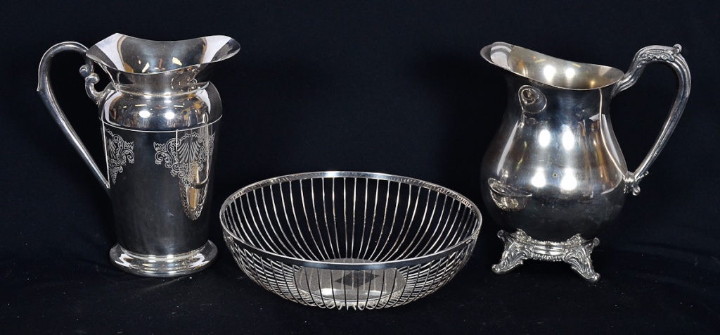Tres peças de metal prateado, sendo 2 jarras e uma cesta para pão.