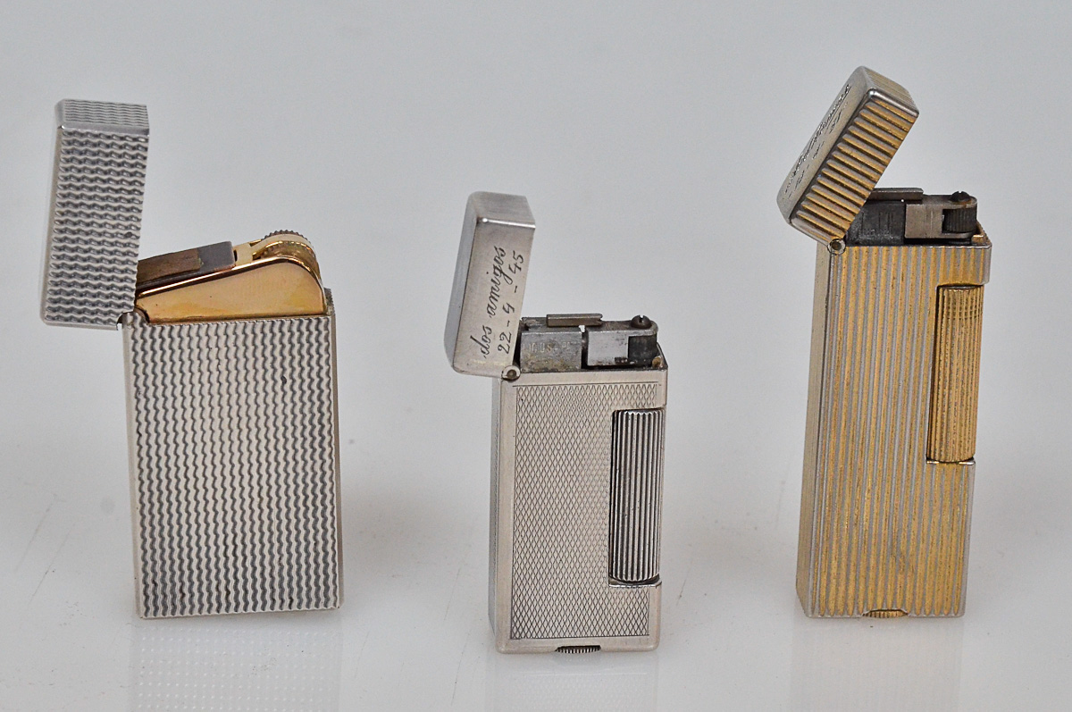 Tres isqueiros diversos, sendo 2 DUNHILL, um dourado com a inscrição...