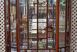 Vitrine de madeira nobre filetada, feitio bombe... - Vitrine de madeira nobre filetada, feitio bombe com vidros bisotados, fundo espelhado. Med. 50 x 1,00 alt. 1,57 m.