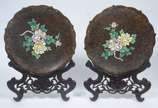 Par de pratos de cloisoné oriental com flores e... - Par de pratos de cloisoné oriental com flores em policromia sobre fundo escuro, bordas recortadas,  bases de madeira entalhada.