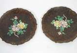 Par de pratos de cloisoné oriental com flores e... - Par de pratos de cloisoné oriental com flores em policromia sobre fundo escuro, bordas recortadas,  bases de madeira entalhada.