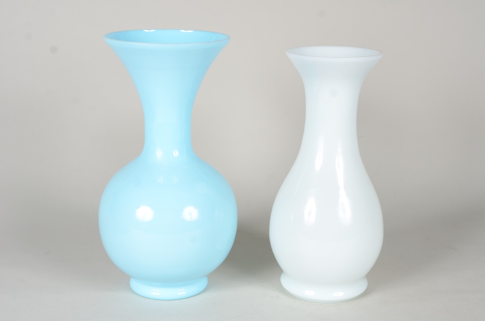 Dois vasos de opalina, sendo um azul e outro branco, feitio balaústre. - foto 1 de 3