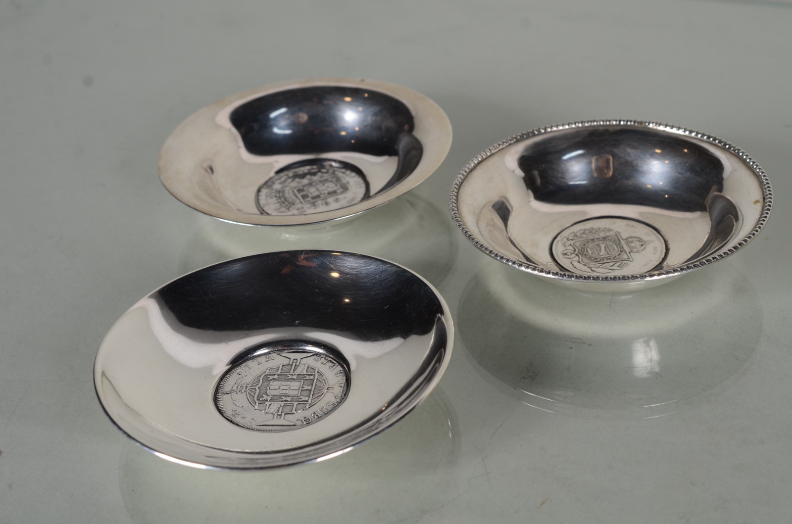 Três cinzeiros de prata com moedas ao centro. Peso da prata: 80 g. - foto 1 de 9