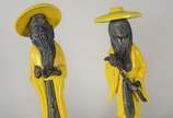 Par de estatuetas orientais de faiança craquelê... - Par de estatuetas orientais de faiança craquelê na cor amarela e metal. (uma delas com o pé da base quebrado).