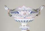 Fruteira de porcelana alemã policromada, base c... - Fruteira de porcelana alemã policromada, base com figura feminina recostada em coluna olhando para figura angelical com guirlandas florais, prat...