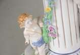 Fruteira de porcelana alemã policromada, base c... - Fruteira de porcelana alemã policromada, base com figura feminina recostada em coluna olhando para figura angelical com guirlandas florais, prat...
