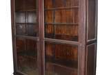 Grande vitrine de madeira nobre com duas portas... - Grande vitrine de madeira nobre com duas portas de correr de vidro e 4 prateleiras internas. Pequena parte quebrada e colada na porta de vidro.