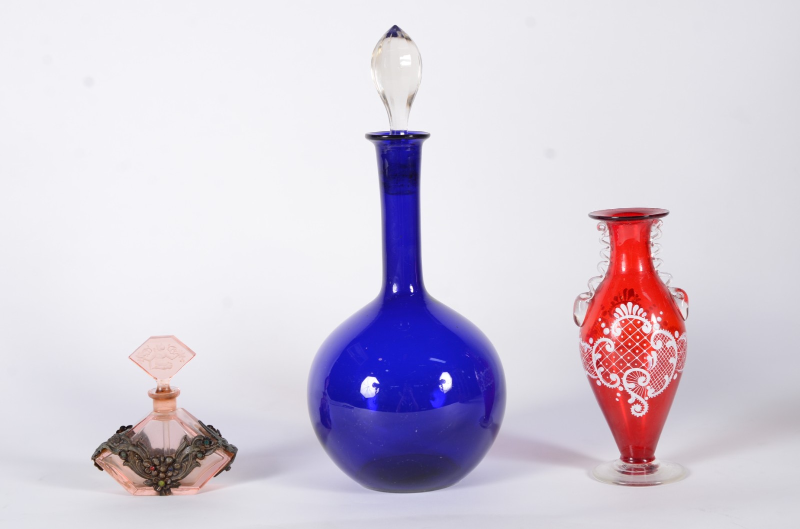 Três peças de vidro, sendo: garrafa azul, vaso vermelho e perfumeiro. - foto 1 de 11
