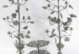 Três peças de metal, sendo: par de luminárias p... - Três peças de metal, sendo: par de luminárias para 7 velas cada, decoradas com pequenos cachos de uvas e folhas de parreira, e fruteira com dois...