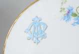Limoges (1771),  - Prato de sobremesa de porcelana francesa Limoges, monogramado, decorado com flores em tons de azul e verde, borda recortada e realçada em dourado.