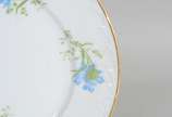 Limoges (1771),  - Prato de sobremesa de porcelana francesa Limoges, monogramado, decorado com flores em tons de azul e verde, borda recortada e realçada em dourado.