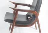 Poltrona com braços e pernas de madeira lustrad... - Poltrona com braços e pernas de madeira lustrada, estofamento forrado em couro sintético preto.