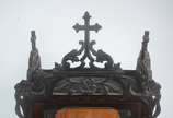 Oratório de madeira nobre, porta e laterais de ... - Oratório de madeira nobre, porta e laterais de vidro circundados por molduras e guirlandas florais recortadas, encimado por crucifixo. Iluminaçã...