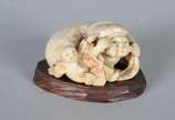 Netsuke de marfim representando figura típica c... - Netsuke de marfim representando figura típica com criança, base de madeira.