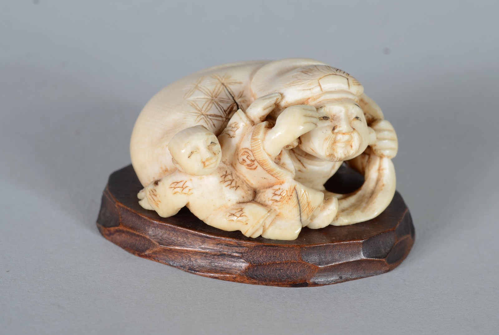 Netsuke de marfim representando figura típica com criança, base de... - foto 1 de 5