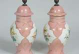 Par de pequenas ânforas de porcelana, fundo ros... - Par de pequenas ânforas de porcelana, fundo rosa com flores pintadas á mão em policromia e realces dourados. Uma delas com rachadura.