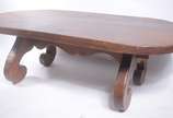 Mesa de centro de madeira nobre, tampo oval apo... - Mesa de centro de madeira nobre, tampo oval apoiado em pernas recortadas.