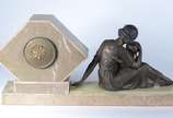 Relógio de mesa Art deco de mármore e ônix deco... - Relógio de mesa Art deco de mármore e ônix decorado com grupo escultórico de metal representando "Figura feminina com criança". Pequeno trincado...