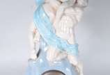 Relógio de mesa encimado por grupo escultórico ... - Relógio de mesa encimado por grupo escultórico de porcelana representando casal se beijando. Com pequenos desgastes e pequenos quebrados, pescoç...
